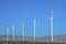 White tubular wind turbines against the mountain range and blue sky in California