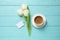 White tulips, coffee and blank tag on light blue wooden table, flat lay with space for text. Good morning