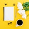 White tulips, notebook, pen, clips with mug of coffee on yellow background. Flat lay, top view.