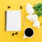 White tulips, notebook and pen with mug of coffee on yellow background. Flat lay, top view.