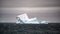 White and turquoise iceberg in dark Southern Ocean with dark and cloudy evening  sky in Antarctica