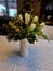 a white twisted vase is filled with flowers and tulips. table with