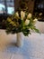a white twisted vase is filled with flowers and tulips. table with