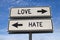 White two street signs with arrow on metal pole with word love and hate