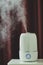 White ultrasonic humidifier on a dark background. Water vapor