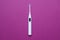 White ultrasonic toethbrush with monitor on purple background, top view
