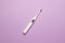 White ultrasonic toethbrush with monitor on purple colored paper background, top view