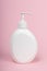 White unbranded dispenser bottle on pink background. Plastic bottle with liquid soap