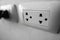 White universal electricity sockets plug on a white wall.