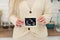 White unrecognisable woman wearing a knitted sweater holding up ultrasound photo of baby to the camera. Close up Indoor