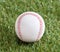 A white used baseball on the fresh green grass