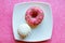 White vanilla zefir and pink donut on white plate, pink glitter background