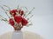 White vase filled with red glitter covered hears and white beaded plant on a cream colored placemat against a white background