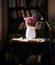 White vase with purple flowers alongside books on a table