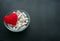 White veg capsules and red thread heart in glass bowl on black b