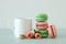 White vintage cup of coffee and colorful macaron or macaroon over pastel wooden table.