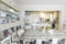 White vintage kitchen with fruit bowls on top of stripped painted wood table and cupboard full