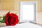 White vintage photo frame and red rose with open diary.