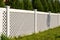 White vinyl fence in a cottage village. Tall Thuja bushes behind the fence