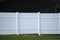 White vinyl picket fence on green lawn surrounding property grounds for backyard protection and privacy