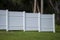 White vinyl picket fence on green lawn surrounding property grounds for backyard protection and privacy