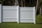 White vinyl picket fence on green lawn surrounding property grounds for backyard protection and privacy