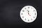 White wall clock on black chalkboard background. Five minutes to midnight