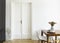 A white wall with double door next to a wooden breakfast table and chairs in a dining room interior. Real photo.