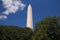 The white Washington obelisk monument with the green trees at the basis