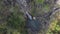 White waterfall with foam on rocky cliff with moss and grass