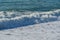 White wave breaking on Sochi Black Sea coast. White spray and foam in the foreground. Emerald blue sea water beyond