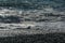 White wave breaking on Sochi Black Sea coast. White spray and foam in the foreground. Emerald blue sea water beyond