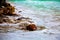 The white wave bumps the brown rocks at the blue sea on brown sand