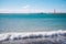 White waves, turquoise sea, bright blue sky, red lighthouse