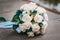 White wedding bouquet of roses and pair of wedding rings on it