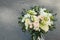 White Wedding Bouquet Roses Pink flowers and Ruscus Leaves with Robbons on Gray Asphalt Background. Wedding Decoration