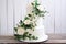 White wedding cake with floral decorations on white background
