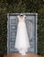 White wedding dress of bride hangs on background of door, boho and rustic style