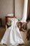 White wedding dress with lace lying on the chair. bouquet different flowers. Modern bridal bunch with poppy flower and