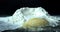 White wheat heap and egg on table. Cooking in front of a black background. Raw chicken egg near mound of flour.