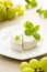 White wheel cheese with basil leaves. Goat cheese on wooden board with basil and grapes