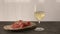 white whine in wine glass on oak table with bresaola on olive board