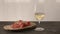 white whine in wine glass on oak table with bresaola on olive board