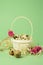 White wicker basket filled with straw,small pink roses,quail eggs on a green background. The concept of Easter Holidays. Easter