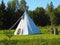 White wigwam on green field.