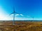 White wind turbine with propellers in a field. Aerial drone view, Clean blue sky, Sunrise time. Renewable eco friendly source of
