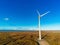 White wind turbine with propellers in a field. Aerial drone view, Clean blue sky, Sunrise time. Renewable eco friendly source of