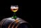 White wine glass stands on an old wooden barrel,.dark background