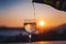 White wine is pouring from a bottle into a glass glass in the sunset with city views