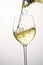White wine pouring to glass from bottle on white background, created using generative ai technology